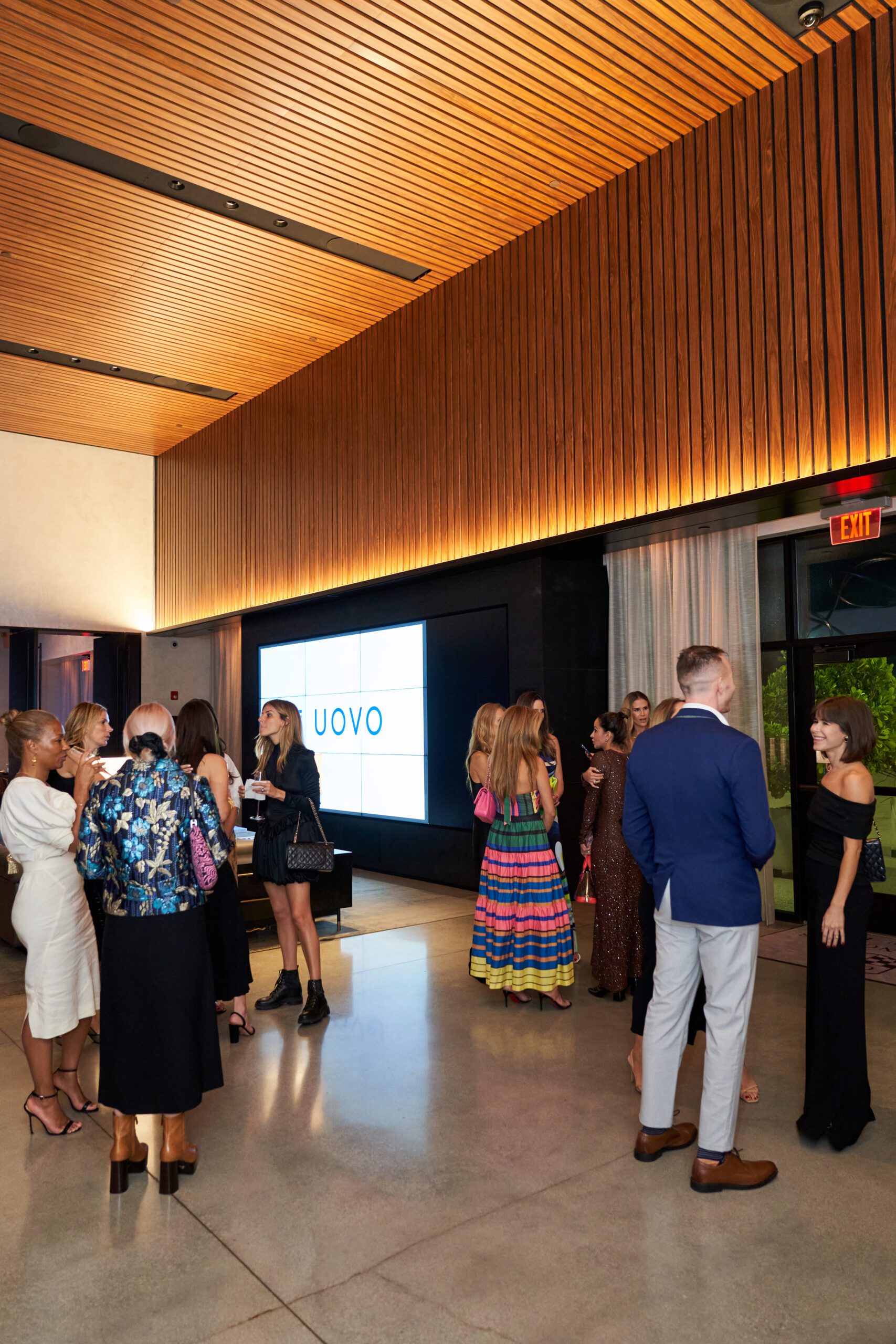 UOVO x Latin American Fashion Summit attendees mingling in front of illuminated screen displaying UOVO branding
