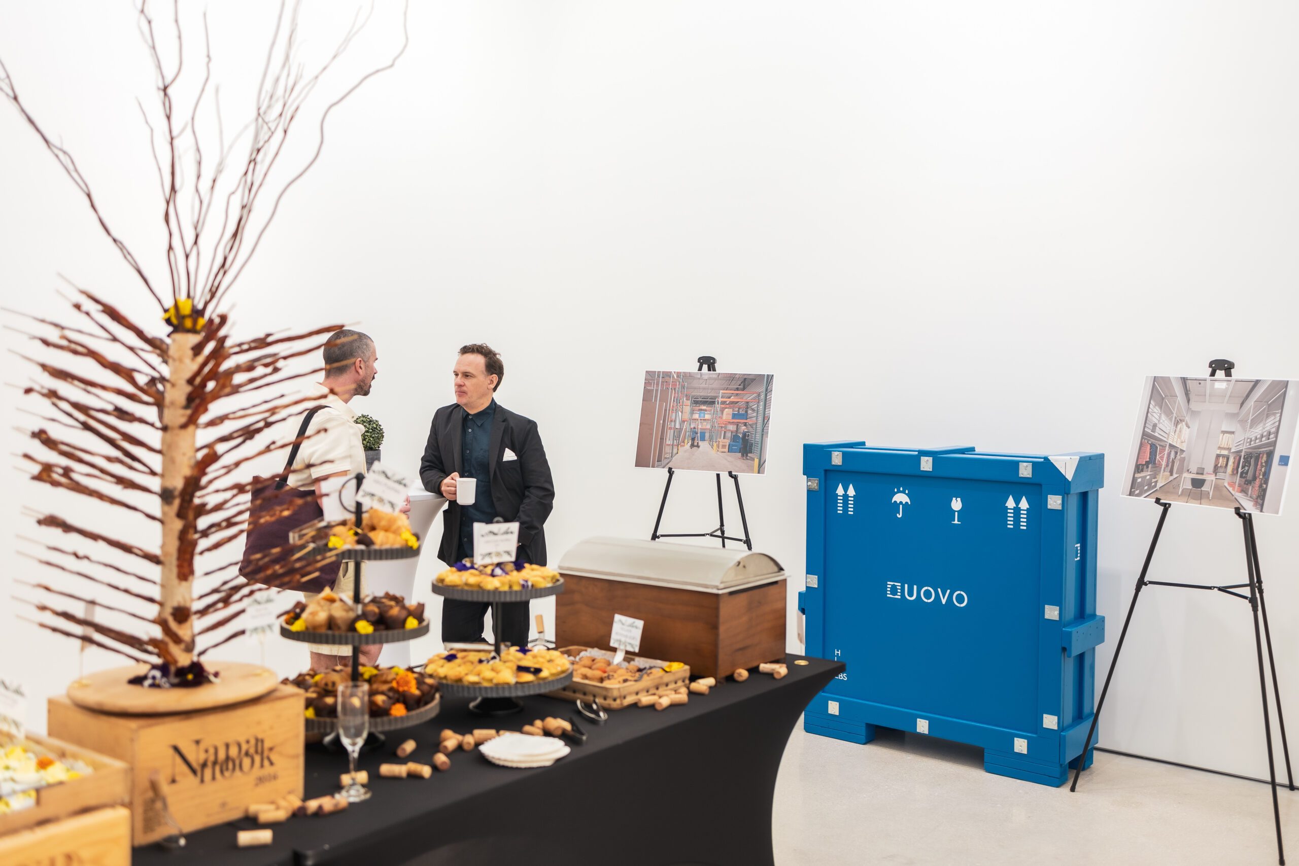 Catering display at panel hosted by UOVO with branded shipping container and facility images on easels.