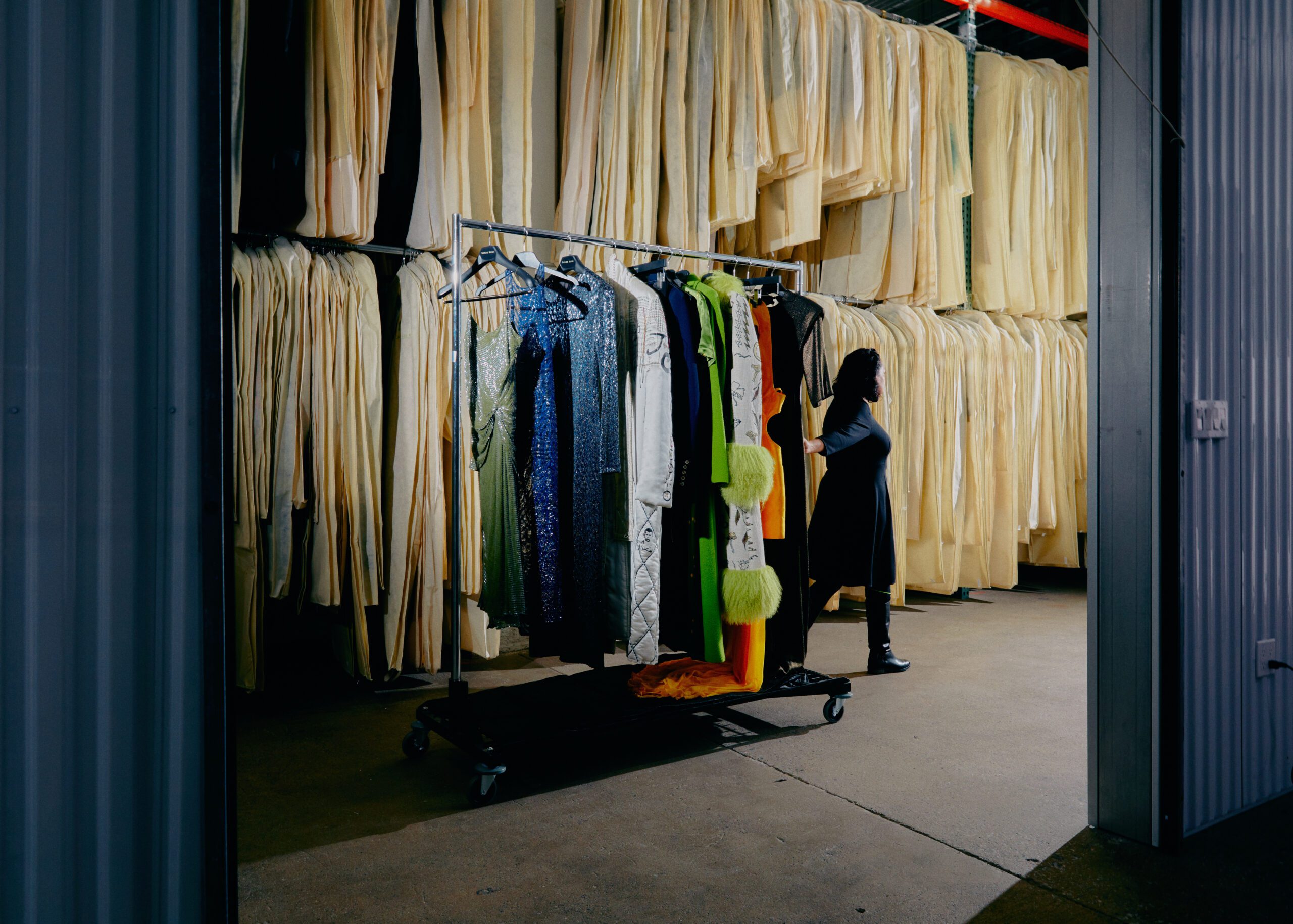 UOVO fashion manager carefully transports a rack of luxury garments through storage facility.