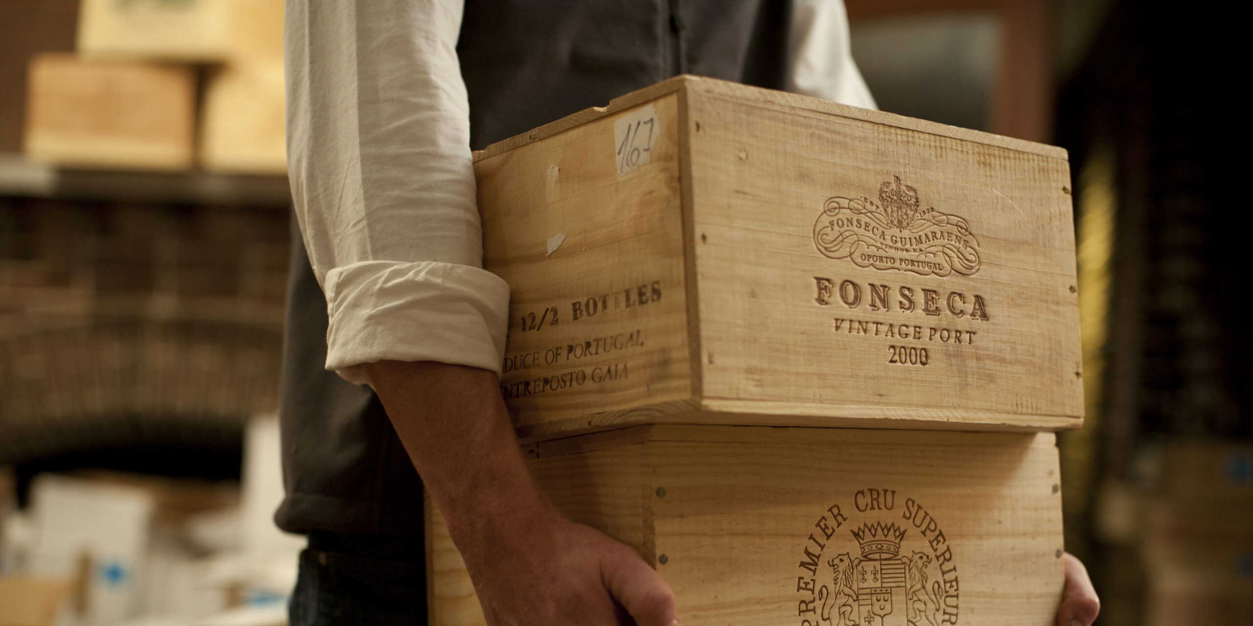 Person Carrying Crates of Wine in Storage