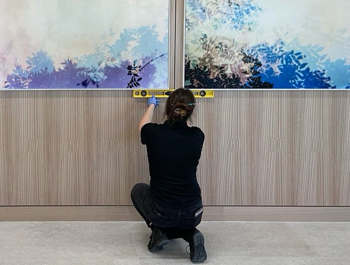 UOVO Houston team member aligning artworks to a wall.