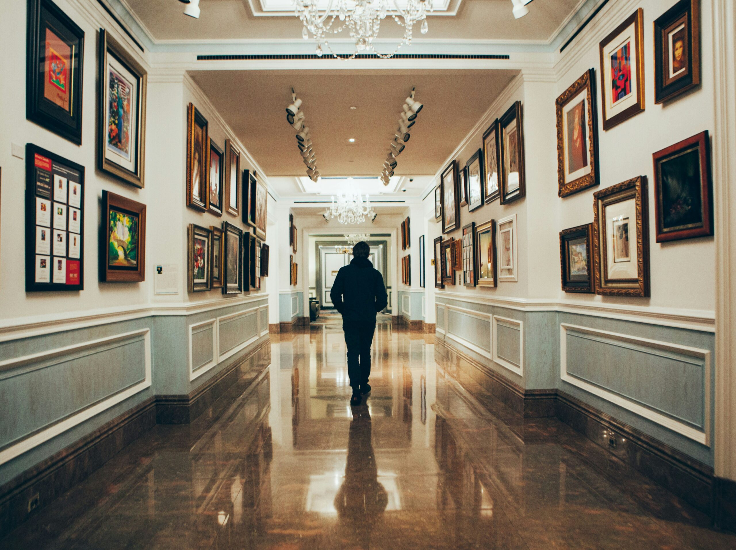 Art collector walking through a hallway with their works on the wall.